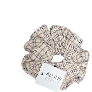 Chouchou élégant à carreaux beige avec des motifs rouges et une étiquette blanche
