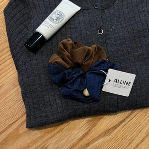 Detailed shot of two-tone corduroy and denim scrunchie with marble bead on grey knitwear