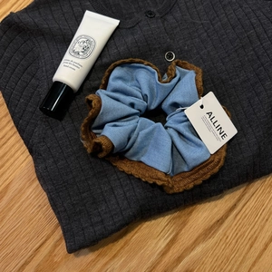 Detail of blue knitted scrunchie with brown edging on a textured sweater background