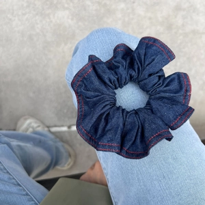 Elastico per capelli in denim con cuciture rosse su sfondo jeans blu chiaro