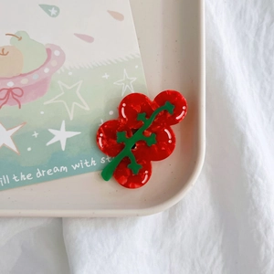 Cute red cherry tomato hair clip made of acetate resin on a minimalist white tray