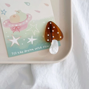 Detail of a brown acetate mushroom hair clip with white dots and pearly white stem texture