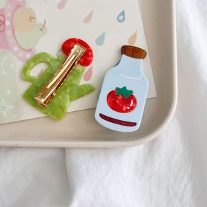 Detail of cute acetate hair clips featuring watering can and tomato sauce bottle shapes