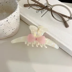 Elegant acetate bunny ear hair claw with pink bow and crystal on a cozy cream background
