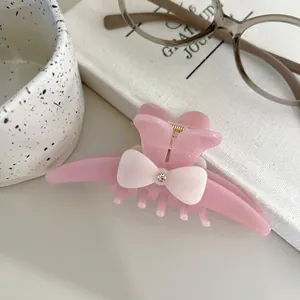 Detail of elegant pink acetate hair claw with cream bow and sparkling rhinestone