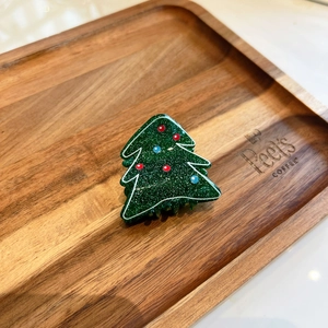 Dettaglio ravvicinato del fermaglio a forma di albero di Natale verde glitterato