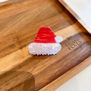 Dettaglio della molletta per capelli in acetato marmorizzato rosso e bianco a forma di Babbo Natale