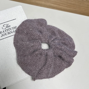 Gros plan d'un chouchou en fourrure de vison gris-violet sur une surface blanche