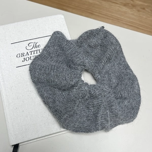 Détail montrant la texture douce du chouchou gris en fausse fourrure sur un livre déco