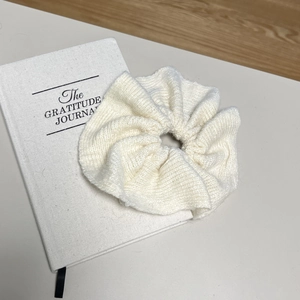 Chouchou élégant en maille côtelée blanc crème sur carnet avec un style minimaliste