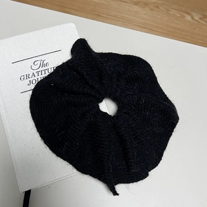 Chouchou élégant en maille de vison noire posé sur un carnet blanc dans un décor de bureau