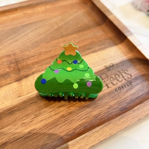 Dettaglio di una molletta per capelli a forma di albero di Natale su sfondo in legno