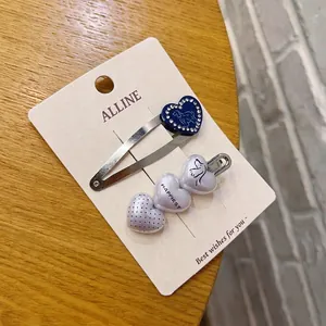 Dettaglio di fermagli per capelli a cuore blu e bianchi con motivi di cani su carta