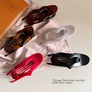 Minimalist heart-shaped hair claw clips set in assorted colors on a soft fabric background