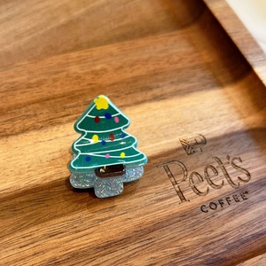 Dettaglio di un fermaglio a forma di albero di Natale verde con luci colorate su vassoio
