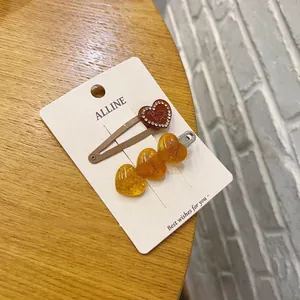 Dettaglio del set di fermagli per capelli a cuore con strass e scritta Happiest su carta
