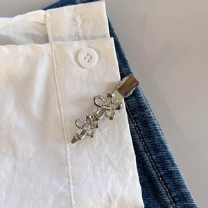 Dettaglio di un fermaglio per capelli a fiore in metallo argentato con strass sui vestiti
