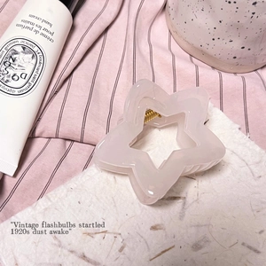 Détail d'une pince à cheveux en forme d'étoile rose translucide avec ressort doré