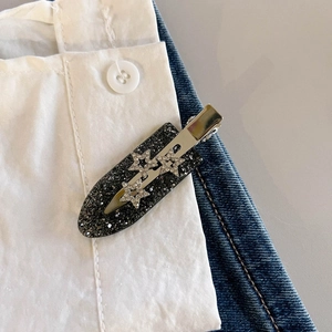 Fermaglio per capelli nero glitterato con tre stelle di strass su sfondo di jeans