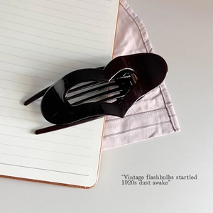 Close-up of a minimalist black heart-shaped hair claw clip on a stylish desk background