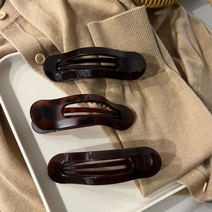Detailed view of three glossy tortoiseshell and brown hair claws on a knitted sweater