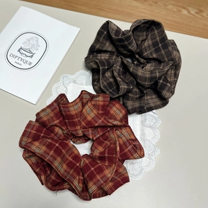 Detail von zwei Vintage-Karo-Stoff-Haargummis in Braun und Rot für das Haarstyling