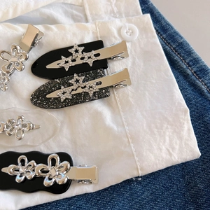 Dettaglio di fermagli per capelli in acetato con stelle, fiori e strass su denim