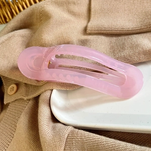 Detailed view of a large matte pink oval hair claw clip on a white ceramic tray