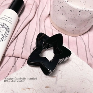 Détail d'une pince à cheveux en forme d'étoile noire brillante sur tissu rose