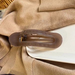 Detail of coffee brown translucent rectangular hair claw clip with golden metal spring
