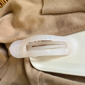 Close-up of a large cream white translucent claw clip on a soft beige knitted fabric
