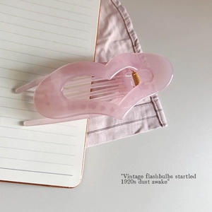Detail of light pink acrylic hair claw clip with golden spring on aesthetic background