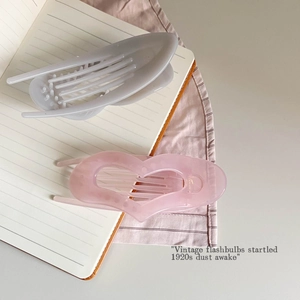 Detail view of a pale pink heart-shaped hair claw clip and grey resin hair accessory