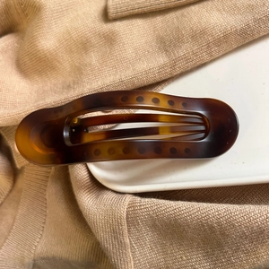 Close-up of brown tortoiseshell hair clip on a ceramic plate and knitted sweater