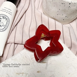 Détail de la pince à cheveux rouge en forme d'étoile creuse avec ressort en métal doré au fond