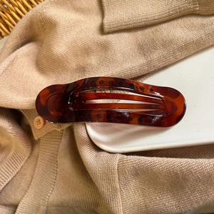 Detailed view of tortoiseshell resin hair claw on ceramic plate with knit background