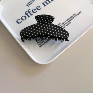 Vintage black and white polka dot acetate hair claw clip on a stylish ceramic tray