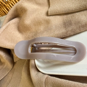Detail of matte mauve oval hair claw clip resting on white porcelain with knit background