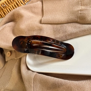 Close-up of a tortoiseshell claw clip on a white plate with cozy knit background