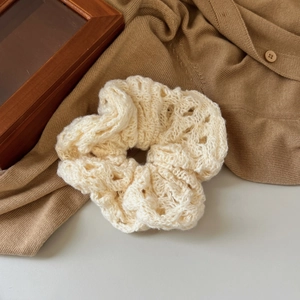 Close-up of cream knit scrunchie featuring delicate hollowed-out crochet texture and patterns