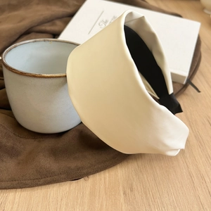 Retro cream white wide PU leather headband with non-slip lining on a wooden desk