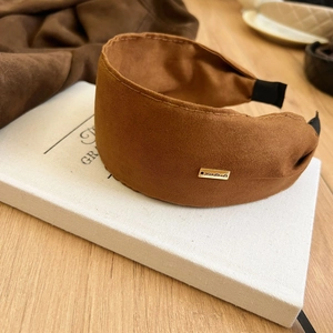 Close-up of brown suede wide headband with a premium handmade engraved gold metal plate