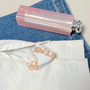 Mini pinza de pelo en acetato crema y melocotón sujeta a un cuello de camisa blanca