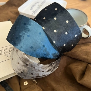 Detailed view of plush velvet polka dot headbands in navy, black, and light grey