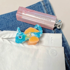Detalle de pinza para el pelo con forma de pez mármol azul y aletas naranjas