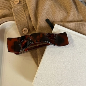 Detail einer dunkel bernsteinfarbenen Haarklammer mit Schildpattmuster auf weißem Tablett
