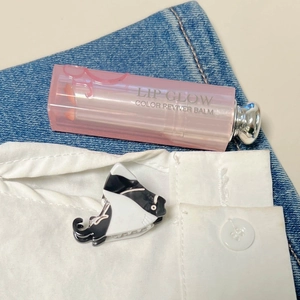 Detalle de una pinza para el pelo de gato blanco y negro y bálsamo labial sobre denim