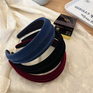 Three velvet headbands in navy, black, and burgundy on a lace fabric background