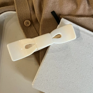 Detail einer eleganten cremeweißen Acetat-Schleifen-Haarklammer auf stilvollem Hintergrund