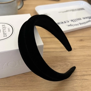 Detailed view of the thick black velvet headband on a textured wooden surface